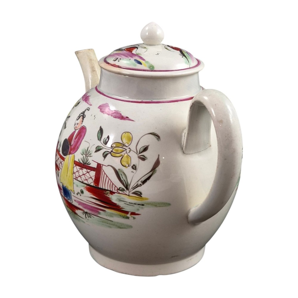 An 18th-century creamware teapot featuring hand-painted polychrome Chinoiserie figures on a cream glaze background with a curved spout and loop handle. View II