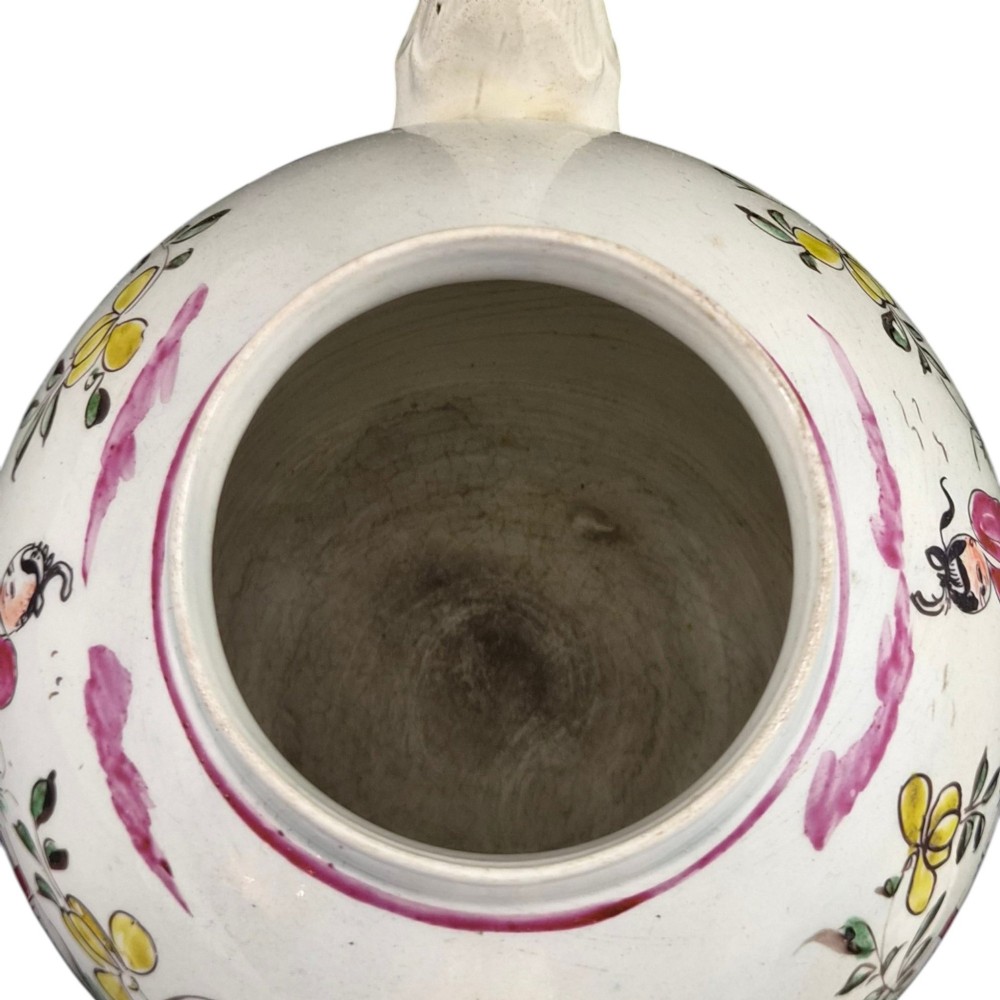 An 18th-century creamware teapot featuring hand-painted polychrome Chinoiserie figures on a cream glaze background with a curved spout and loop handle. View VIII