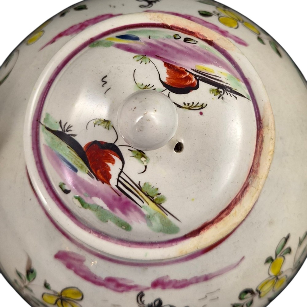 An 18th-century creamware teapot featuring hand-painted polychrome Chinoiserie figures on a cream glaze background with a curved spout and loop handle. View X