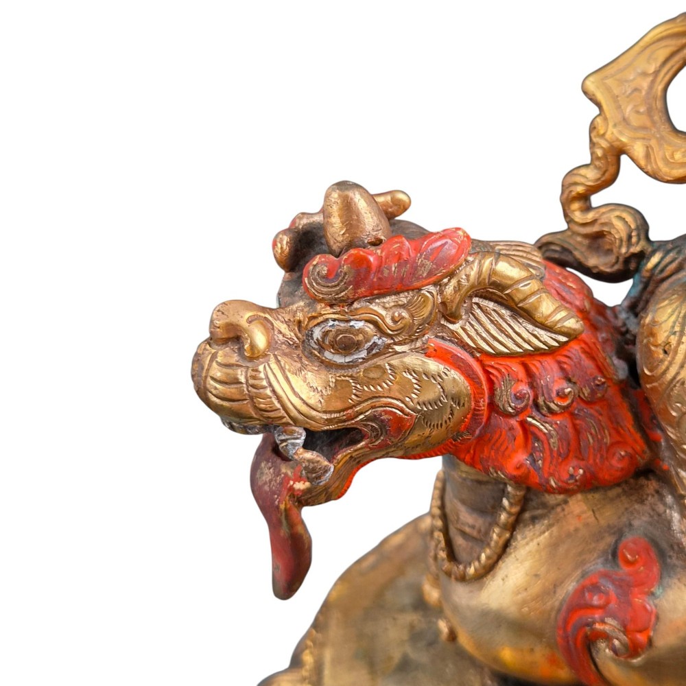 A gilt bronze figure of the deity Jambhala crowned and adorned with jewellery, seated upon a snow lion atop an oval lotus pedestal base with red and blue painted accents. View X