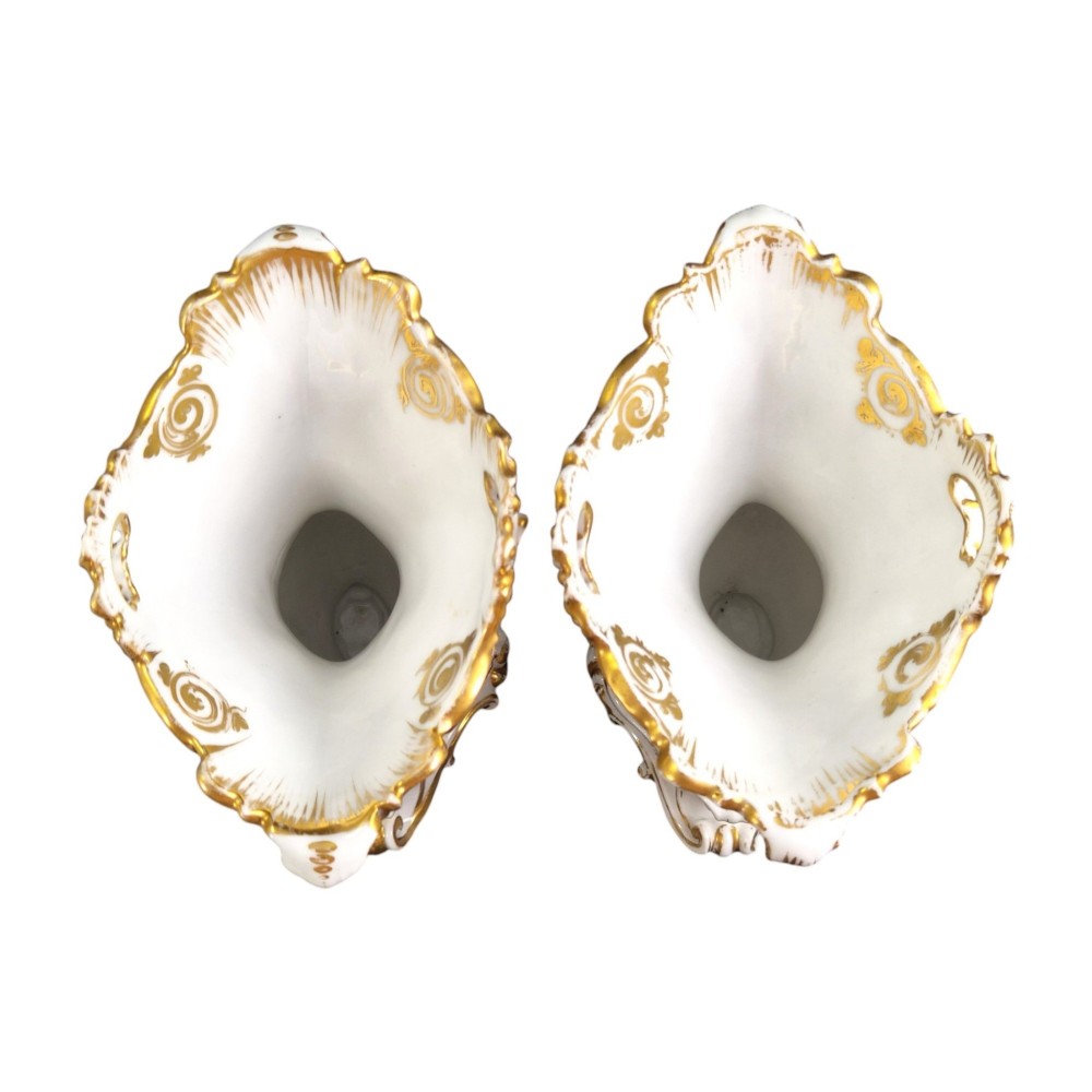 A pair of ornate white and gilded porcelain Rococo vases featuring hand-painted floral bouquets, pierced rims, and scroll handles. View V
