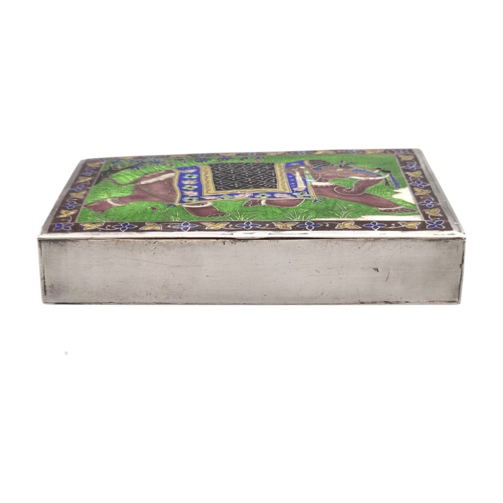 A rectangular sterling silver box featuring a colourful enamelled scene of a decorated Indian elephant set against a green background with a patterned border. View X
