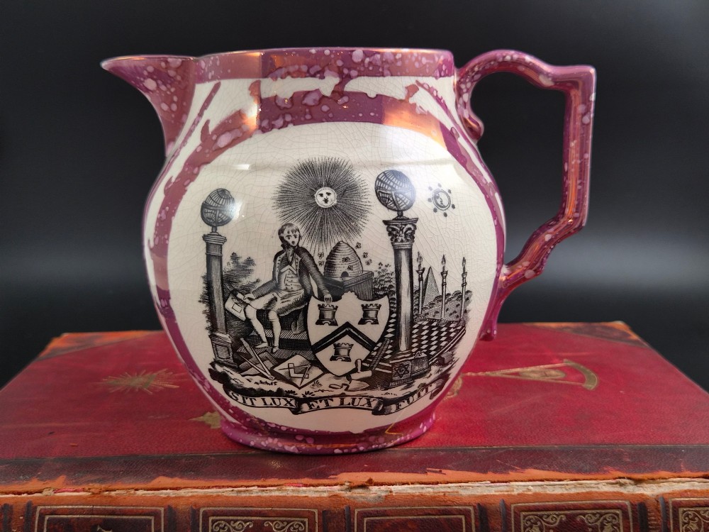 An English earthenware jug featuring pink splash lustre glaze trim and a central black transfer-printed Masonic emblem.