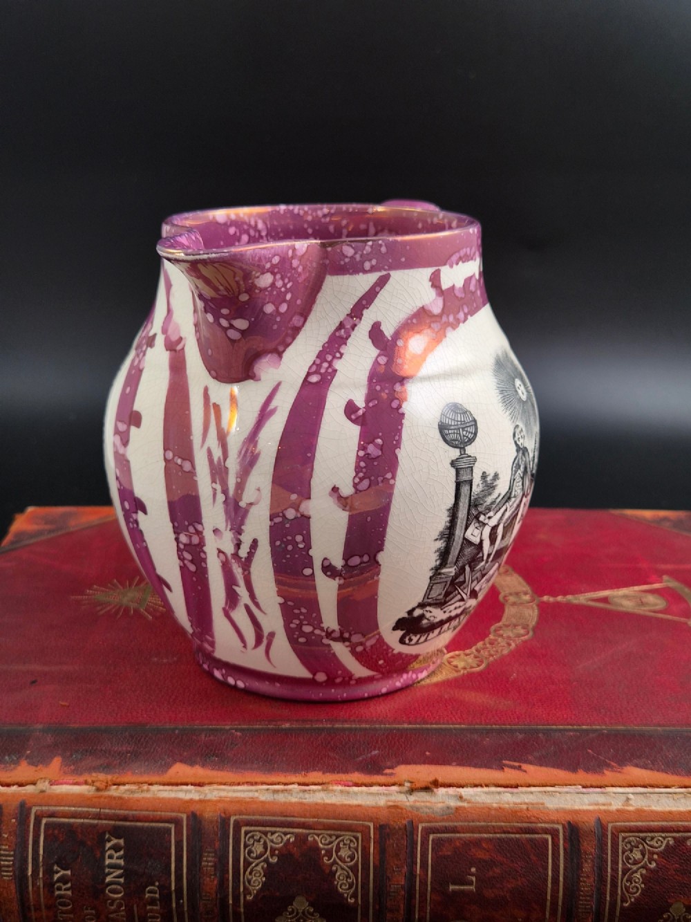 An English earthenware jug featuring pink splash lustre glaze trim and a central black transfer-printed Masonic emblem. View VI
