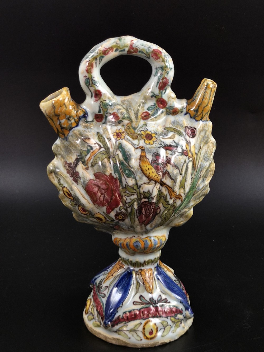 An 18th-century Italian majolica pilgrim flask featuring a scallop-shell body, twin spouts, loop handles, a pedestal foot, and hand-painted polychrome flora and fauna.