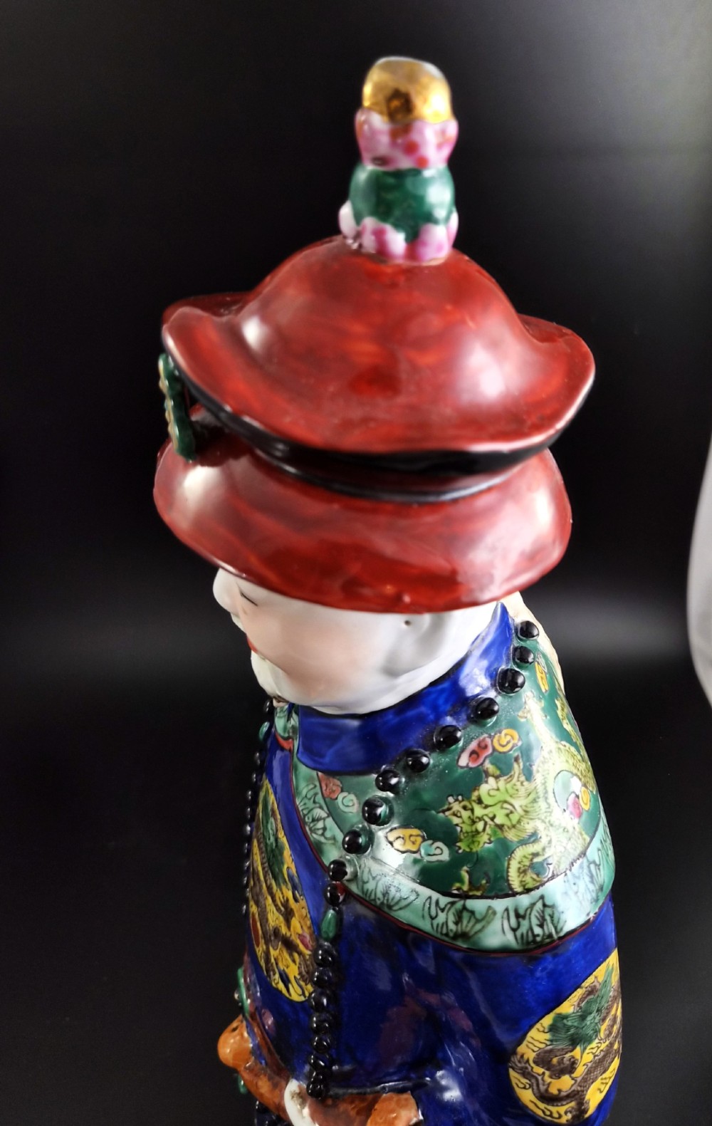 A pair of tall Chinese porcelain figures wearing traditional Qing Dynasty imperial robes in bright yellow and royal blue, adorned with dragon roundels and court beads. View VI