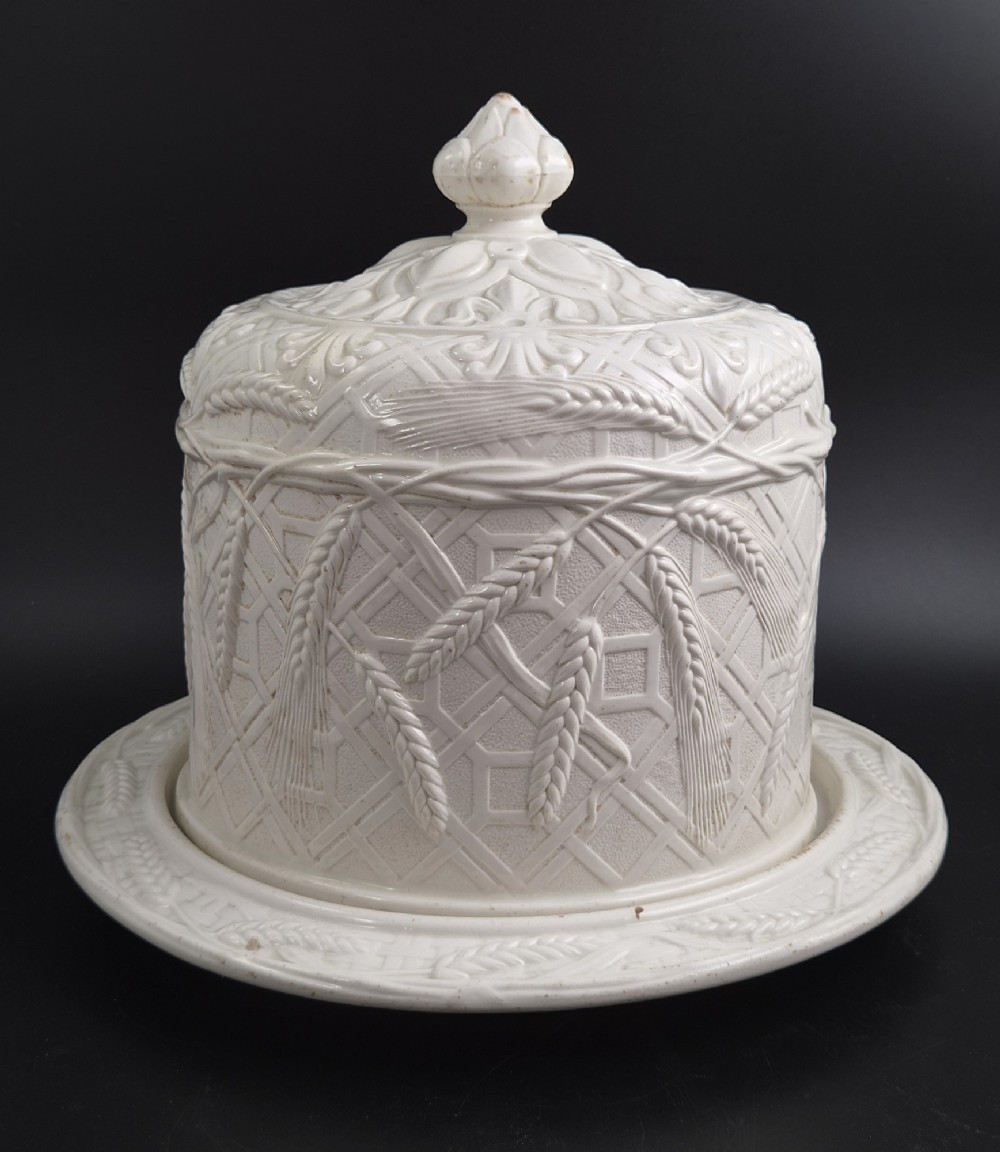 An off-white Victorian ironstone cheese dome and matching circular stand with molded relief lattice work and wheat sheaf motifs. View II