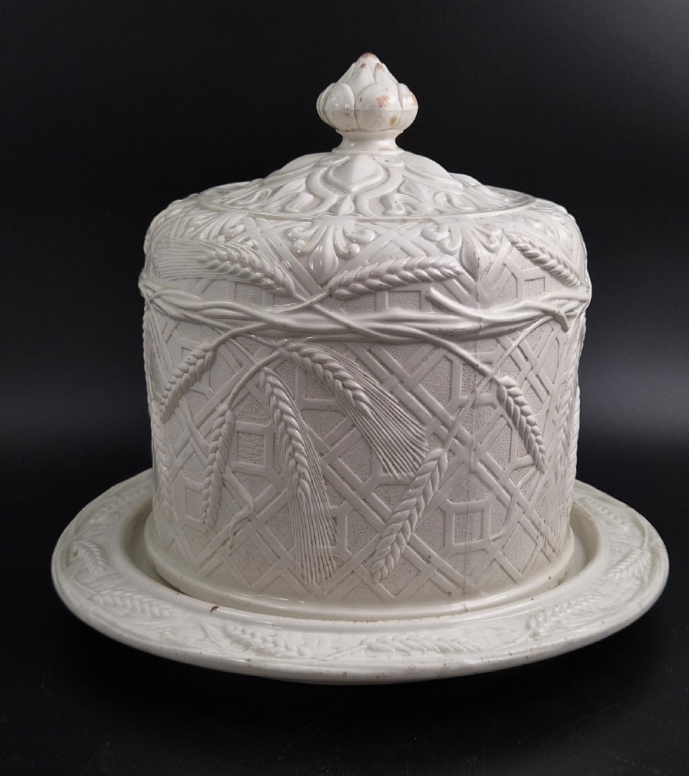 An off-white Victorian ironstone cheese dome and matching circular stand with molded relief lattice work and wheat sheaf motifs. View III