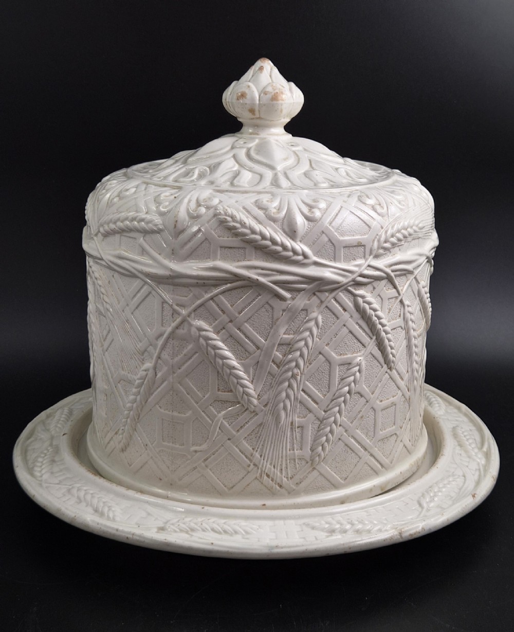 An off-white Victorian ironstone cheese dome and matching circular stand with molded relief lattice work and wheat sheaf motifs. View IV