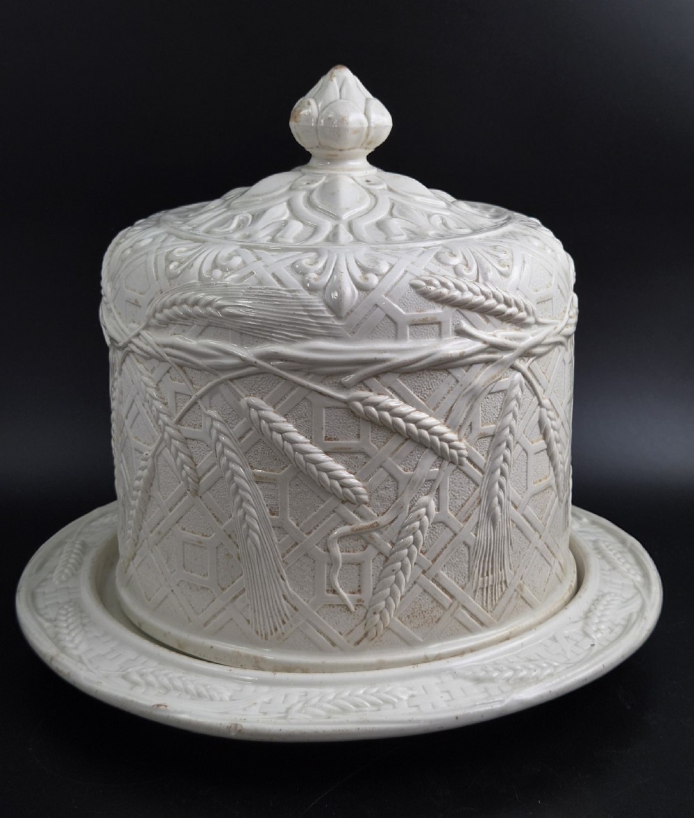An off-white Victorian ironstone cheese dome and matching circular stand with molded relief lattice work and wheat sheaf motifs. View VI