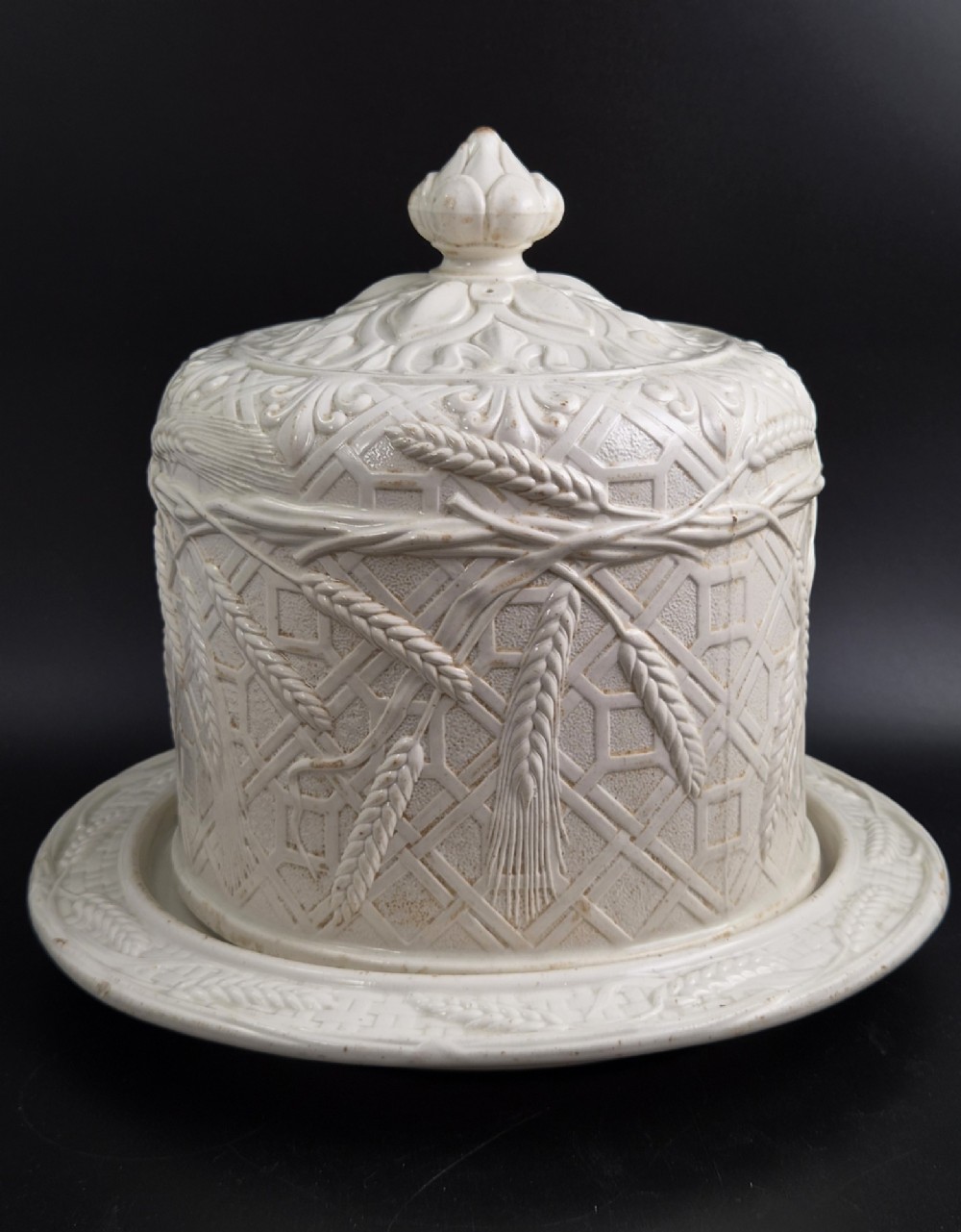An off-white Victorian ironstone cheese dome and matching circular stand with molded relief lattice work and wheat sheaf motifs. View VII