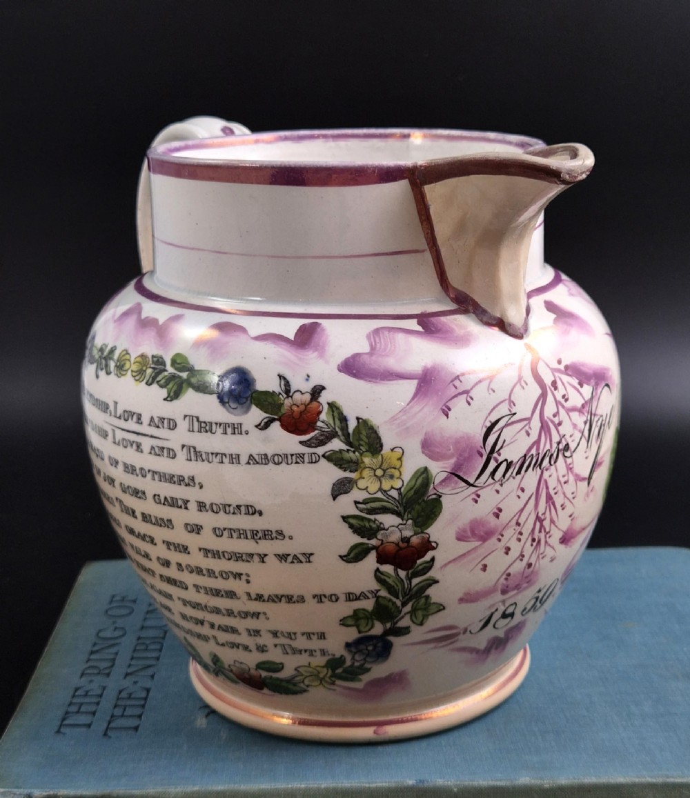 An antique cream earthenware jug decorated with pink splash lustre glaze and a central transfer print depicting the Iron Bridge over the Wear. View V