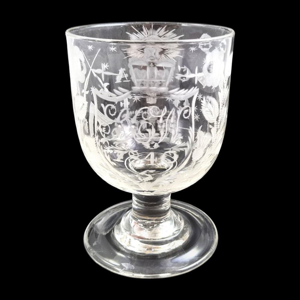A clear lead-glass rummer featuring detailed wheel-engraved fraternal symbols, including a central cross, all-seeing eye, crowns, and floral garlands, resting on a short stem and circular foot. View V