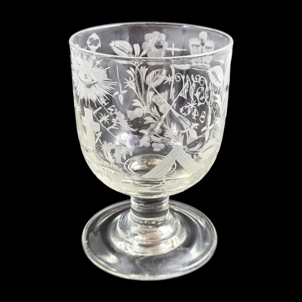 A clear lead-glass rummer featuring detailed wheel-engraved fraternal symbols, including a central cross, all-seeing eye, crowns, and floral garlands, resting on a short stem and circular foot. View IX