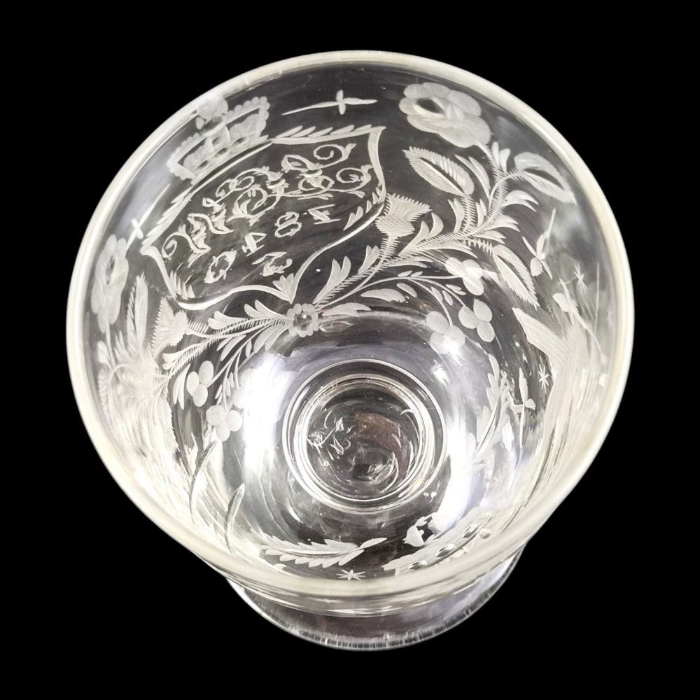 A clear lead-glass rummer featuring detailed wheel-engraved fraternal symbols, including a central cross, all-seeing eye, crowns, and floral garlands, resting on a short stem and circular foot. View X