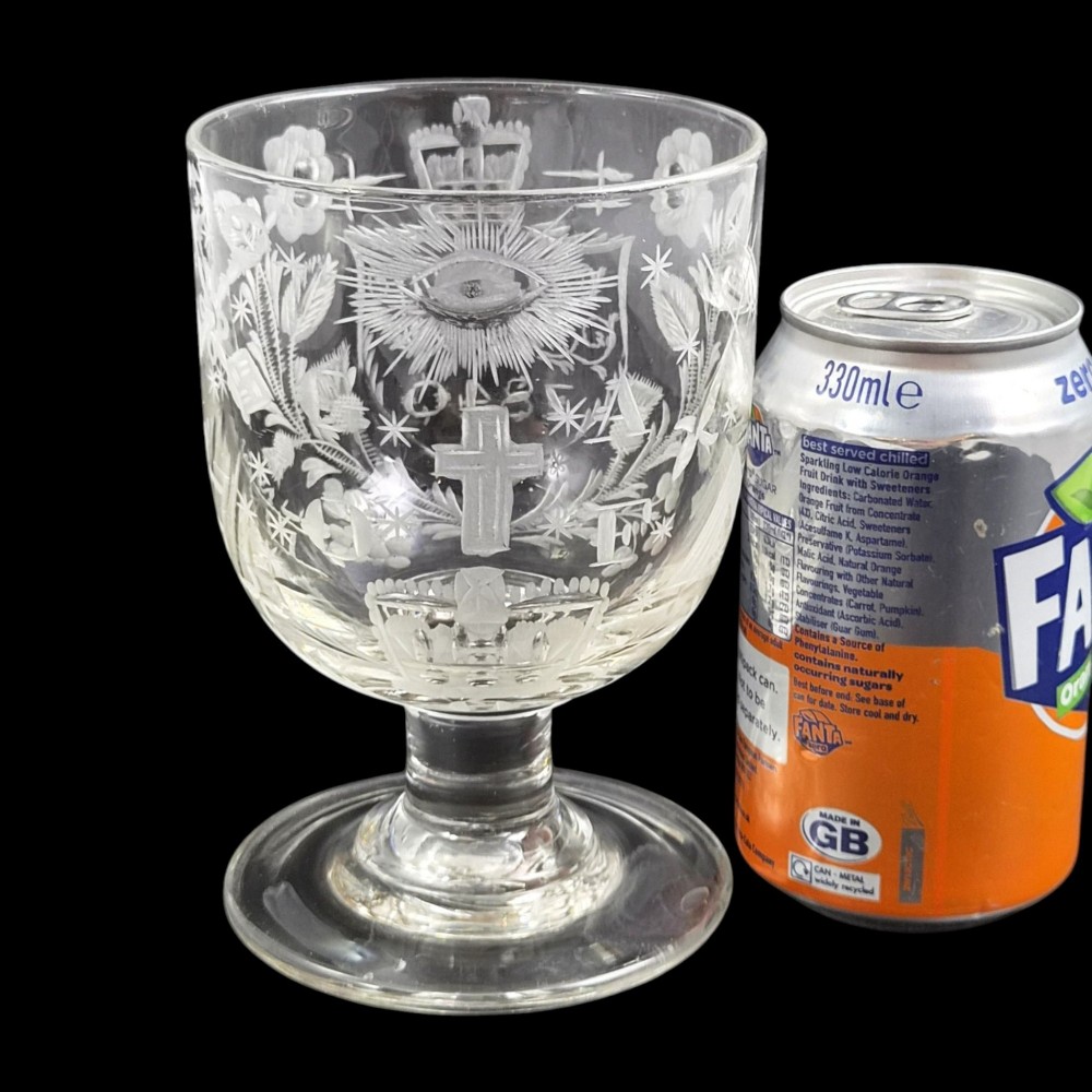 A clear lead-glass rummer featuring detailed wheel-engraved fraternal symbols, including a central cross, all-seeing eye, crowns, and floral garlands, resting on a short stem and circular foot. View XII