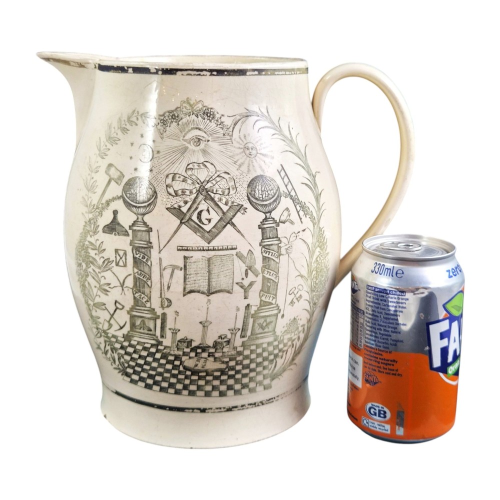 A Georgian Staffordshire creamware jug featuring transfer-printed olive-green Masonic iconography framed by a leafy scrollwork wreath. View II