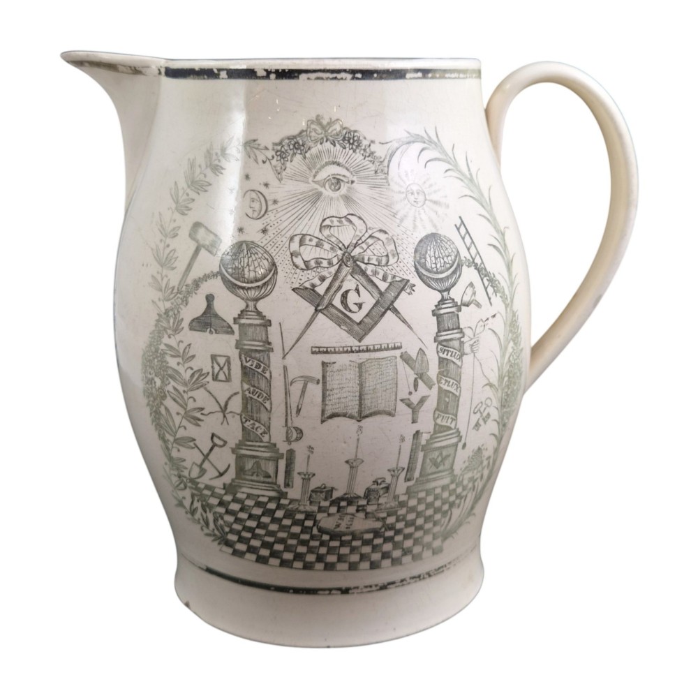 A Georgian Staffordshire creamware jug featuring transfer-printed olive-green Masonic iconography framed by a leafy scrollwork wreath. View V