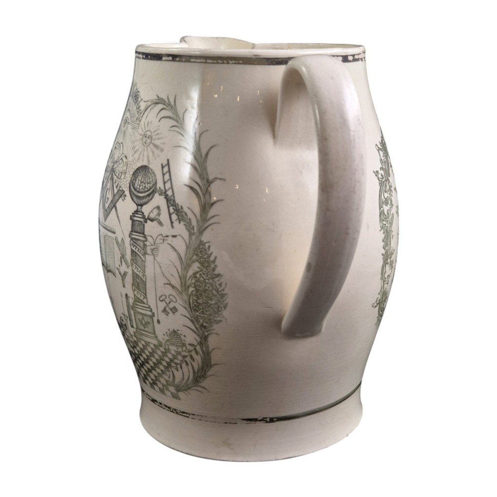 A Georgian Staffordshire creamware jug featuring transfer-printed olive-green Masonic iconography framed by a leafy scrollwork wreath. View VI