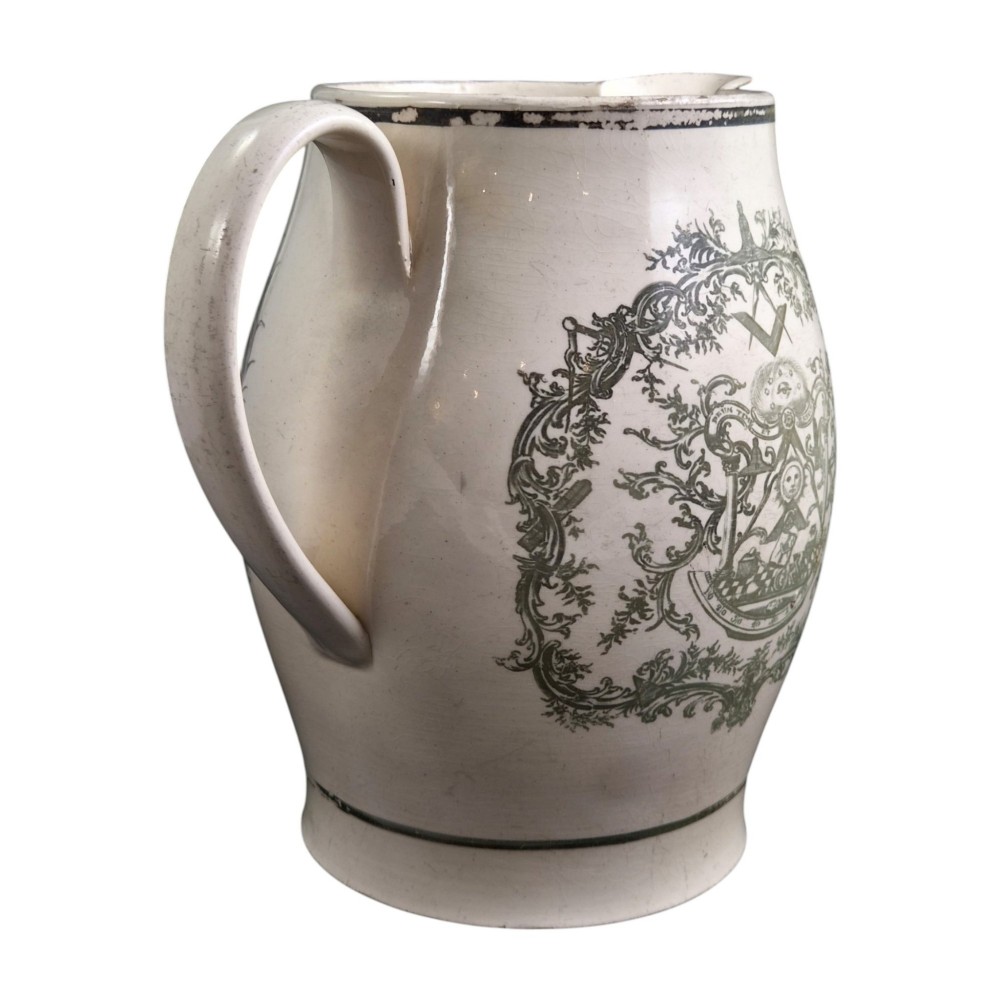 A Georgian Staffordshire creamware jug featuring transfer-printed olive-green Masonic iconography framed by a leafy scrollwork wreath. View VII