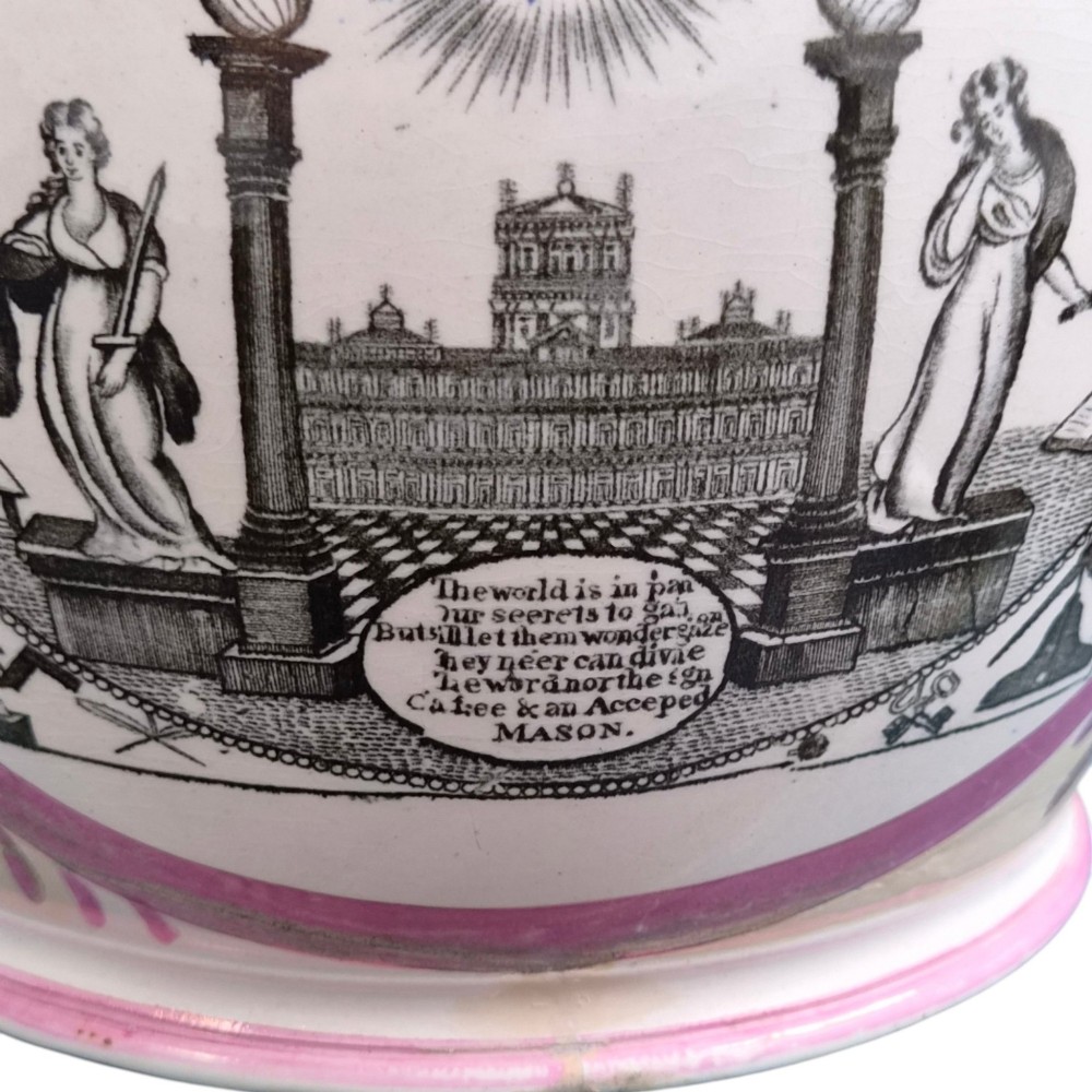 An antique white earthenware jug decorated with pink metallic lustre foliage borders and a black transfer-printed Masonic emblem featuring twin columns and symbolic motifs. View VIII