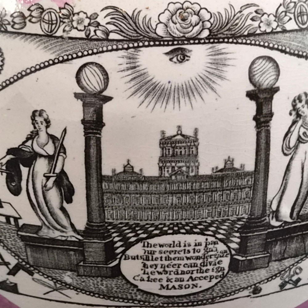 An antique white earthenware jug decorated with pink metallic lustre foliage borders and a black transfer-printed Masonic emblem featuring twin columns and symbolic motifs. View IX