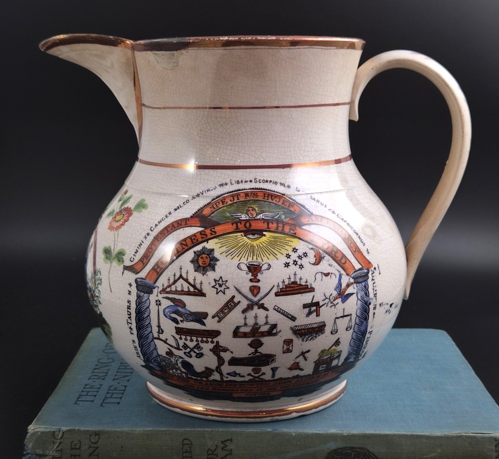 A cream earthenware jug featuring hand-painted floral motifs, copper lustre trim, and a printed Orange Order emblematic coat of arms with religious and fraternal symbols. View III