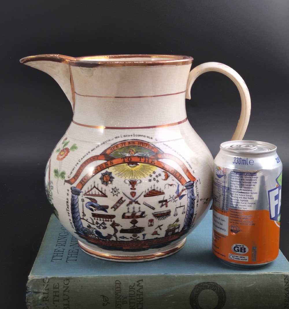 A cream earthenware jug featuring hand-painted floral motifs, copper lustre trim, and a printed Orange Order emblematic coat of arms with religious and fraternal symbols. View XI