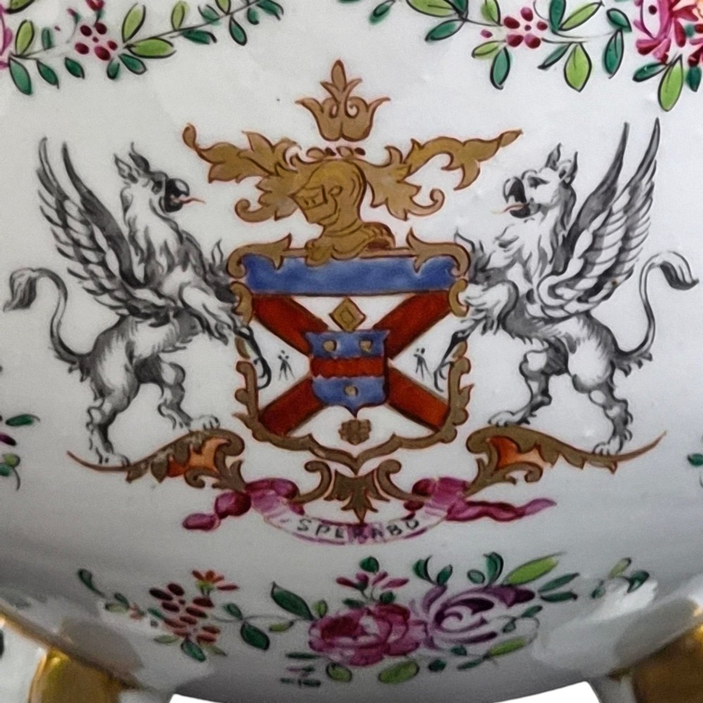 A white hard-paste porcelain covered jar on three cabriole legs, decorated with floral enamel sprays, an armorial crest, green lattice borders, and topped with a foo dog lid finial. View VIII