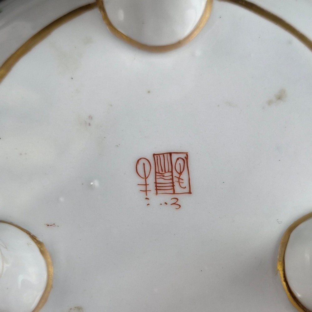 A white hard-paste porcelain covered jar on three cabriole legs, decorated with floral enamel sprays, an armorial crest, green lattice borders, and topped with a foo dog lid finial. View XIII
