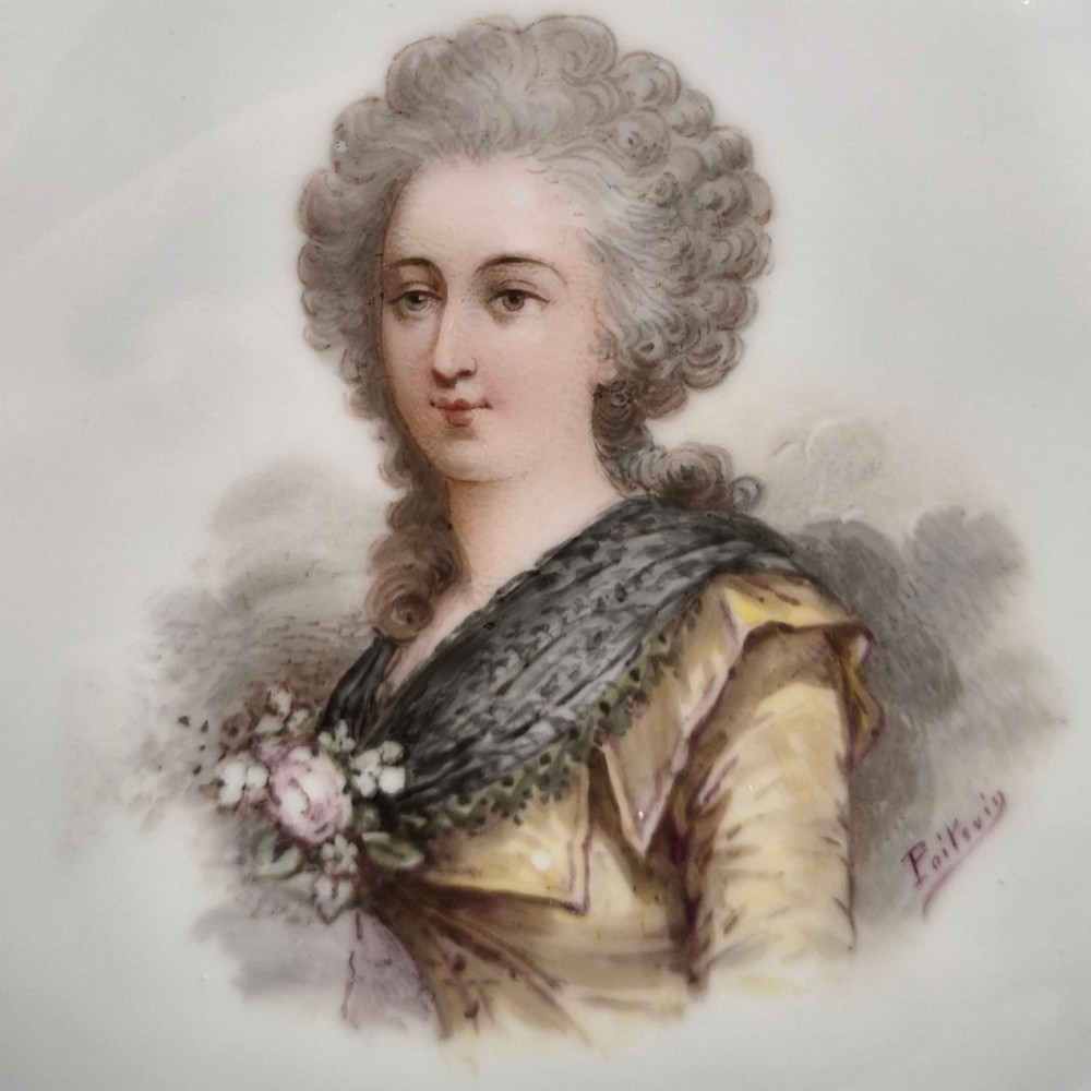 A circular porcelain cabinet plate featuring a central hand-painted portrait of a woman framed by a deep cobalt blue rim with gold scrollwork. View IX