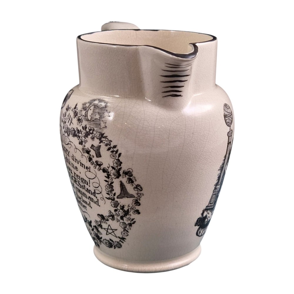 A creamware ceramic jug featuring detailed black transfer prints of Masonic emblems, including classical columns, a beehive, and a coat of arms. View V