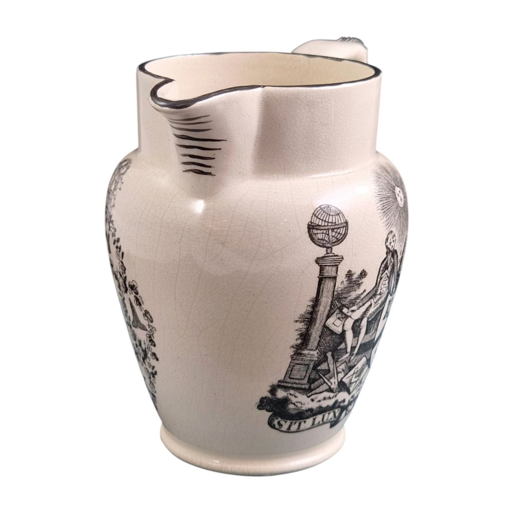 A creamware ceramic jug featuring detailed black transfer prints of Masonic emblems, including classical columns, a beehive, and a coat of arms. View VI