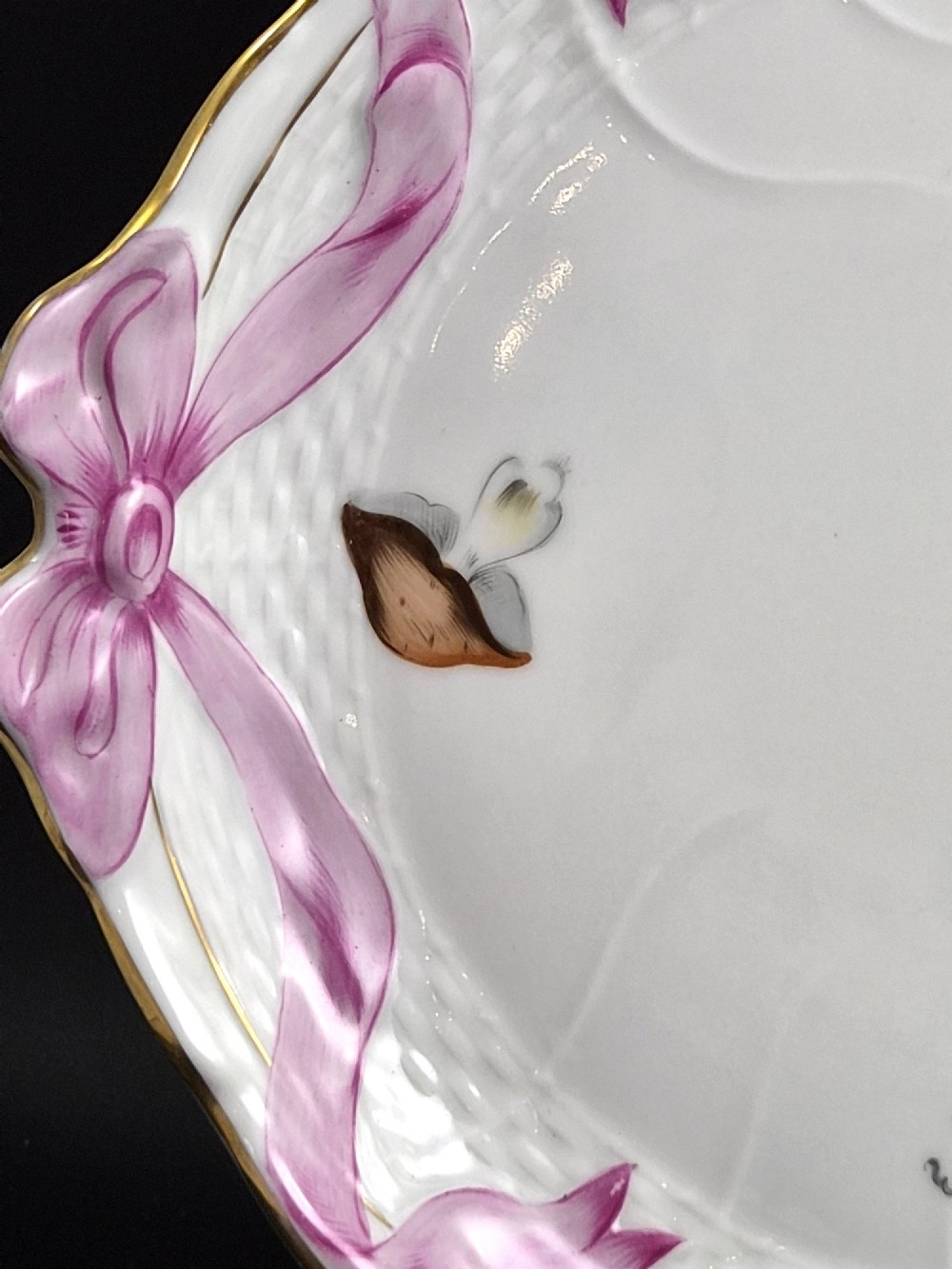 An oval white porcelain tray featuring hand-painted fruit and insect motifs, moulded basketweave border, pink painted ribbon handles, and a gilded rim. View IV