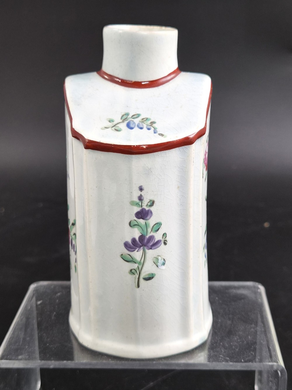 An eighteenth-century creamware tea canister with hand-painted floral enamel motifs in purple, red, and green on an off-white earthenware body with arched reddish-brown shoulders. View II