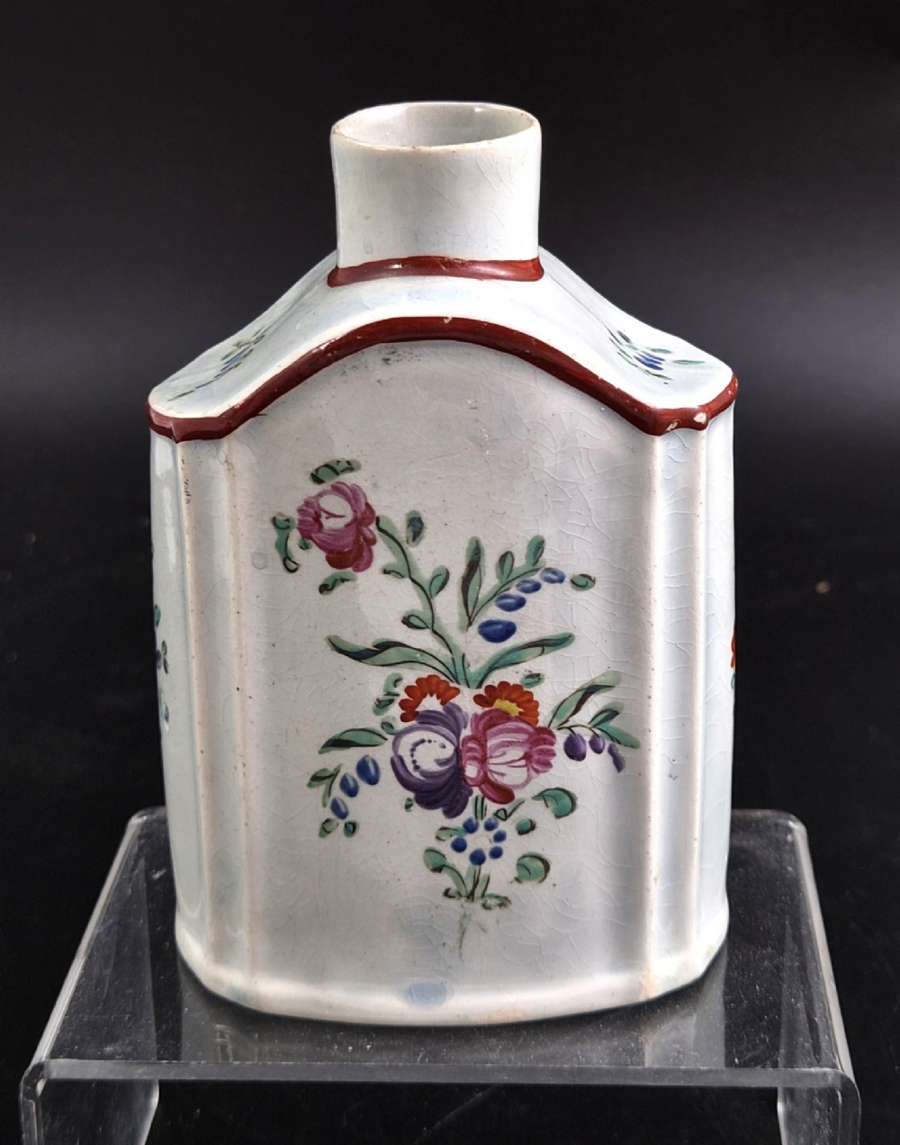 An eighteenth-century creamware tea canister with hand-painted floral enamel motifs in purple, red, and green on an off-white earthenware body with arched reddish-brown shoulders. View III