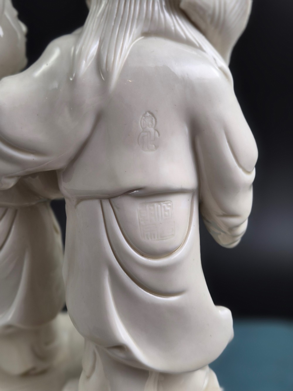 A Qing Dynasty Blanc-de-Chine white porcelain figure group depicting the Hehe Erxian standing on a stylised lotus and wave base. View IX