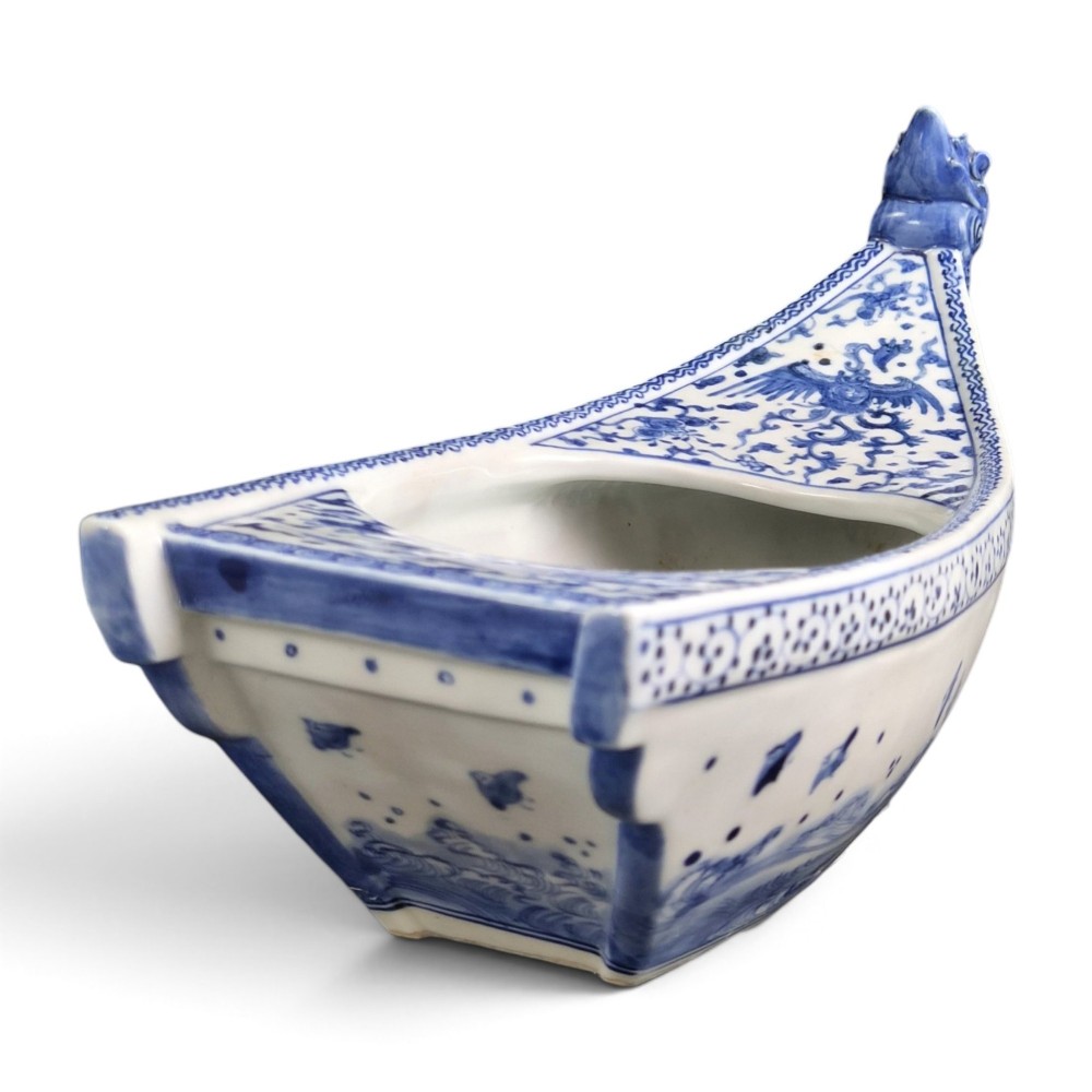 A Japanese blue and white porcelain vessel shaped like a boat featuring a carved dragon figurehead at the prow. View VIII