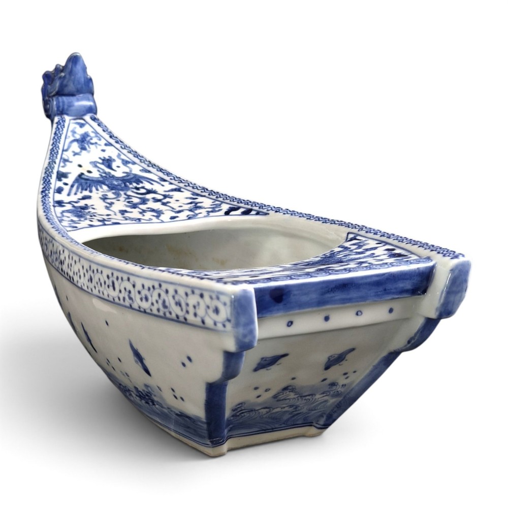 A Japanese blue and white porcelain vessel shaped like a boat featuring a carved dragon figurehead at the prow. View IX