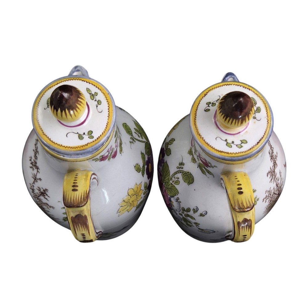 A pair of 18th-century white tin-glazed earthenware oil and vinegar jugs decorated with hand-painted floral motifs and fitted with yellow finial covers. View II