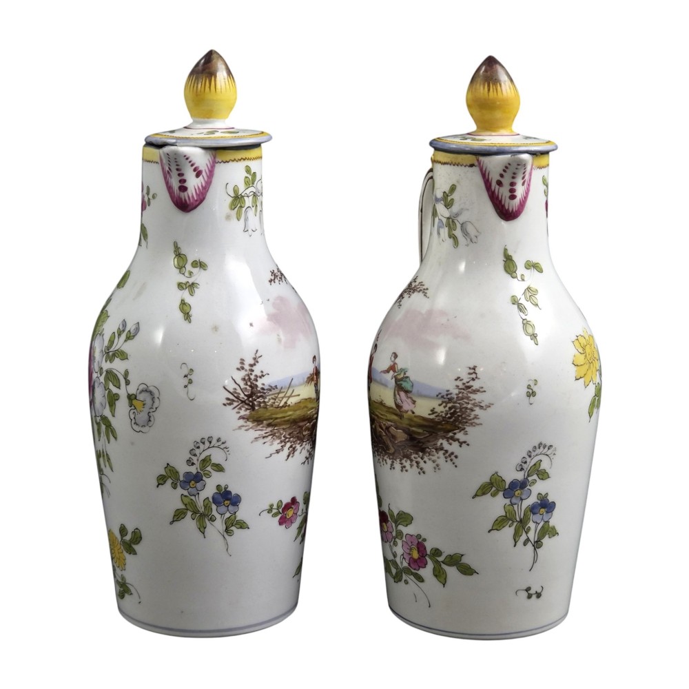 A pair of 18th-century white tin-glazed earthenware oil and vinegar jugs decorated with hand-painted floral motifs and fitted with yellow finial covers. View VI