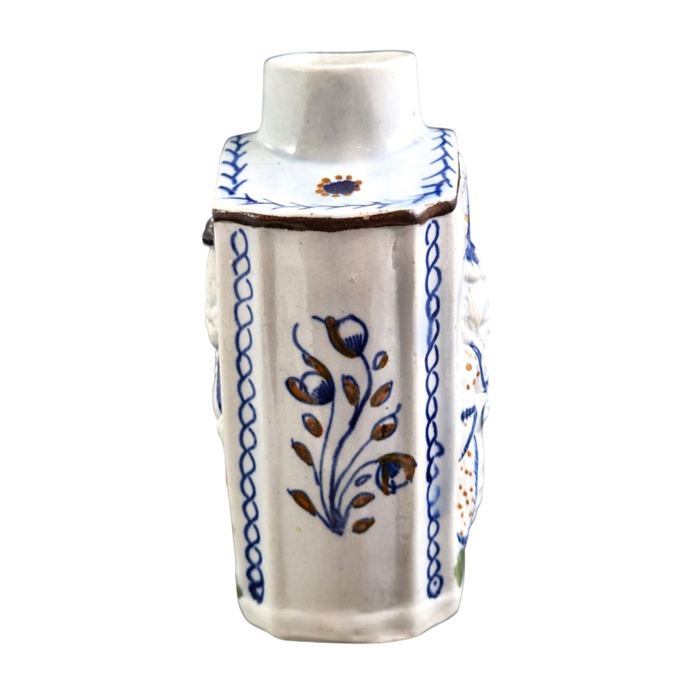 An 18th-century Prattware earthenware tea canister featuring relief-moulded depictions of two Georgian Macaroni figures in blue, ochre, and green underglaze glazes against an off-white background. View IV