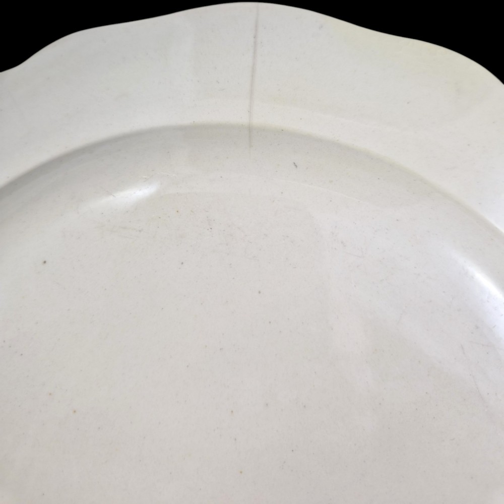 A pair of round cream-coloured earthenware plates featuring monochrome transfer prints of birds and moulded scalloped rims. View VII