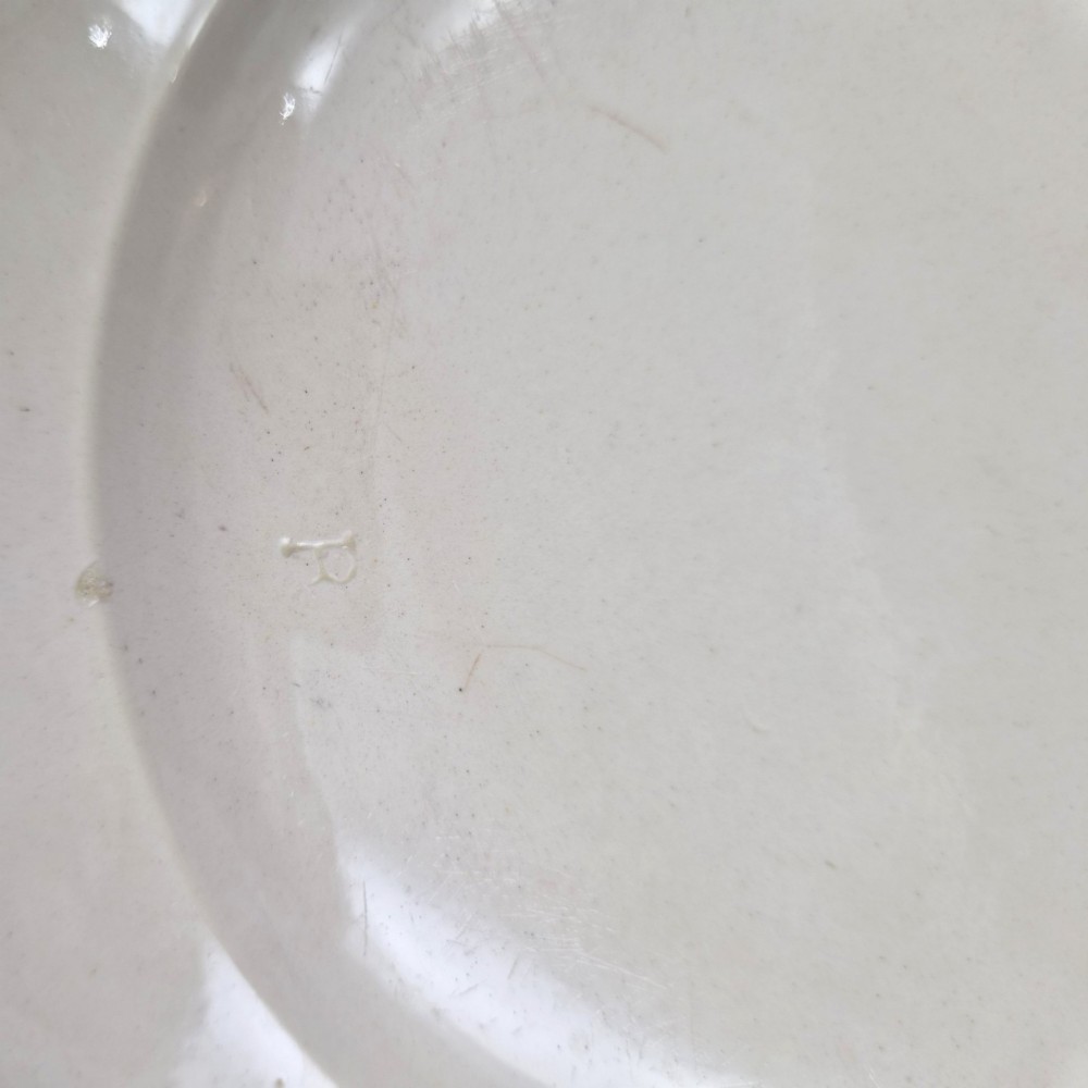 A pair of round cream-coloured earthenware plates featuring monochrome transfer prints of birds and moulded scalloped rims. View X