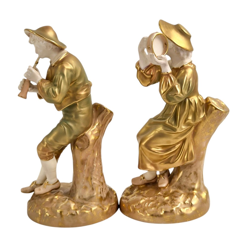 A pair of mid-century Royal Worcester bone china figurines depicting Strephon playing a pipe instrument and Phyllis playing a tambourine, finished in metallic gold and off-white porcelain. View II