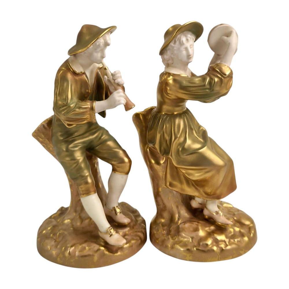 A pair of mid-century Royal Worcester bone china figurines depicting Strephon playing a pipe instrument and Phyllis playing a tambourine, finished in metallic gold and off-white porcelain. View V