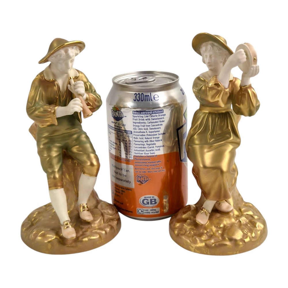 A pair of mid-century Royal Worcester bone china figurines depicting Strephon playing a pipe instrument and Phyllis playing a tambourine, finished in metallic gold and off-white porcelain. View X