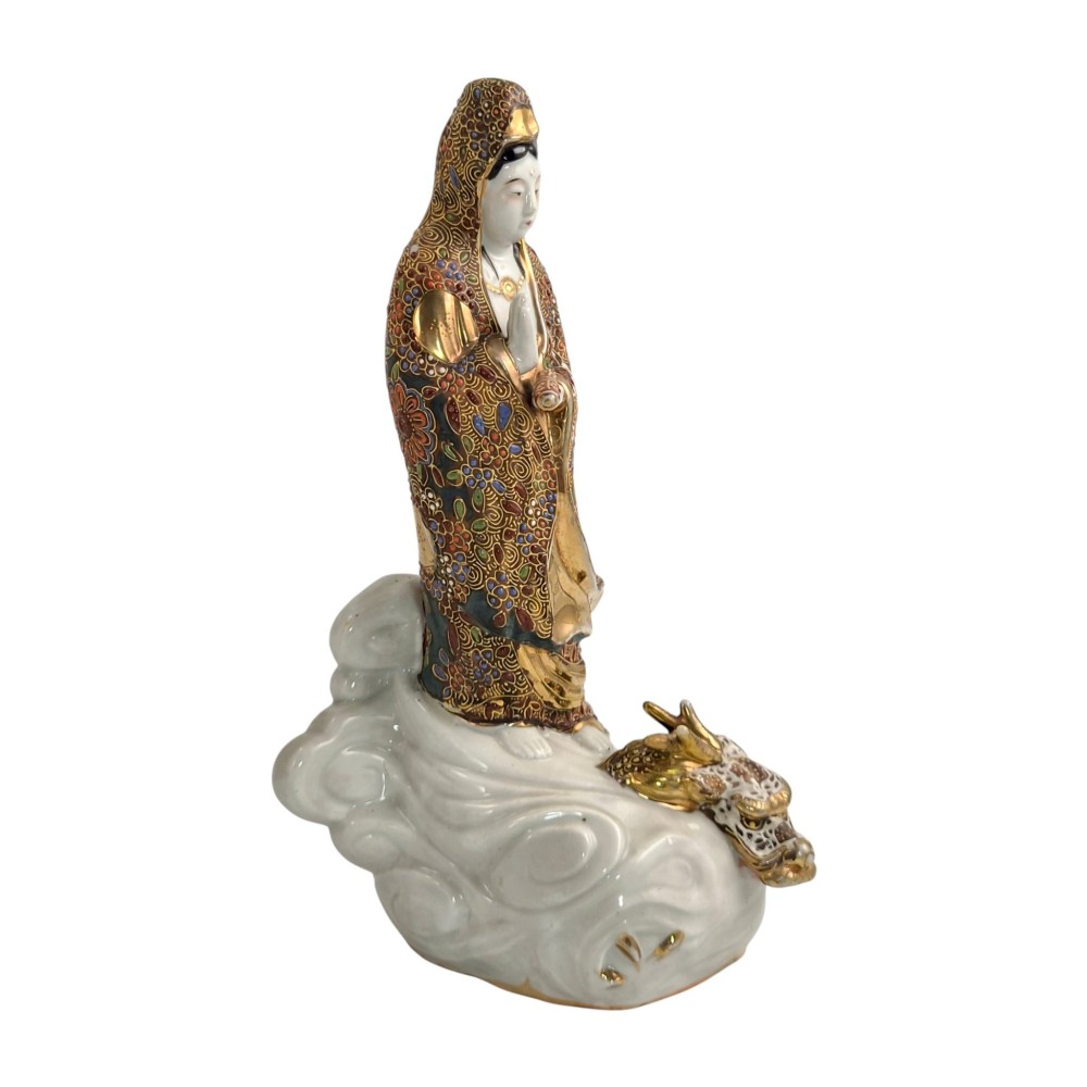 A Japanese Kutani porcelain figure of the deity Kannon in detailed patterned robes, standing atop a white sea dragon amidst sculpted waves. View VII