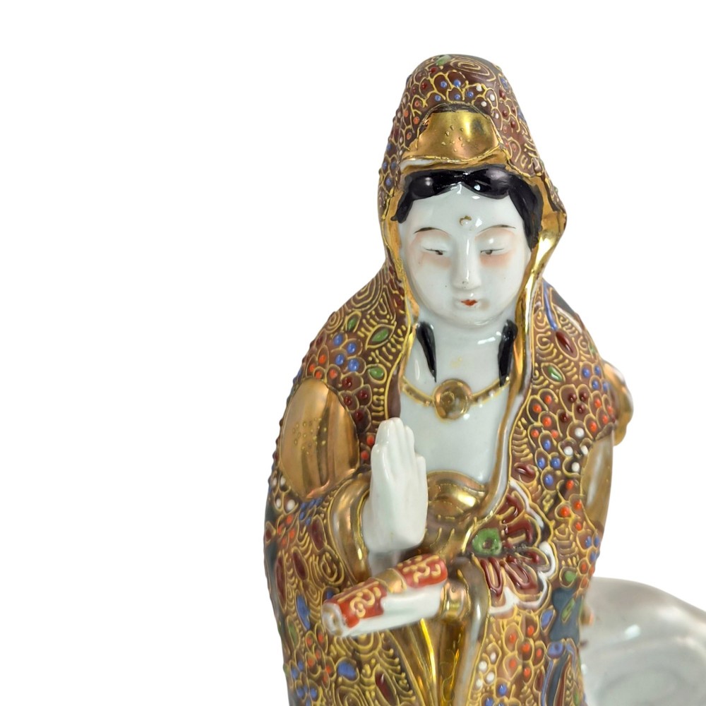 A Japanese Kutani porcelain figure of the deity Kannon in detailed patterned robes, standing atop a white sea dragon amidst sculpted waves. View IX