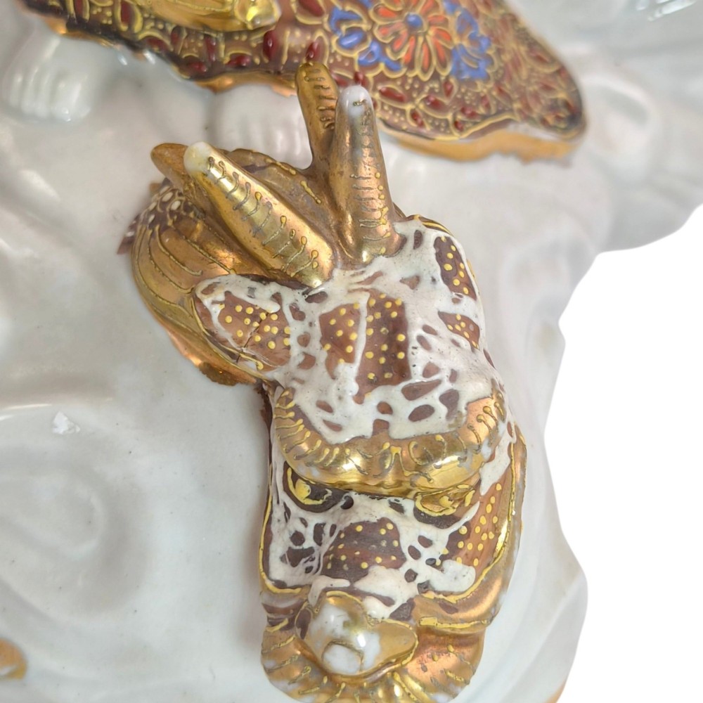 A Japanese Kutani porcelain figure of the deity Kannon in detailed patterned robes, standing atop a white sea dragon amidst sculpted waves. View X